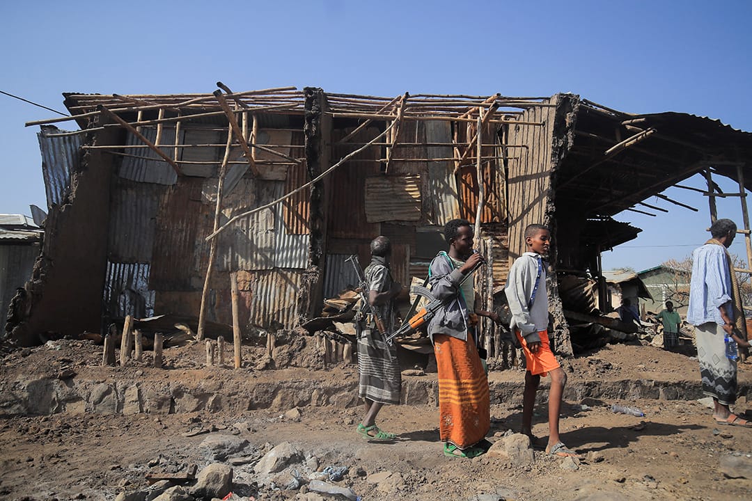 Residents and militias stand next to houses destroyed by an airstrike during the fight between the Ethiopian National Defence Forces (ENDF) and the Tigray People's Liberation Front (TPLF) forces in Kasagita town, Afar region, Ethiopia, February 25, 2022.