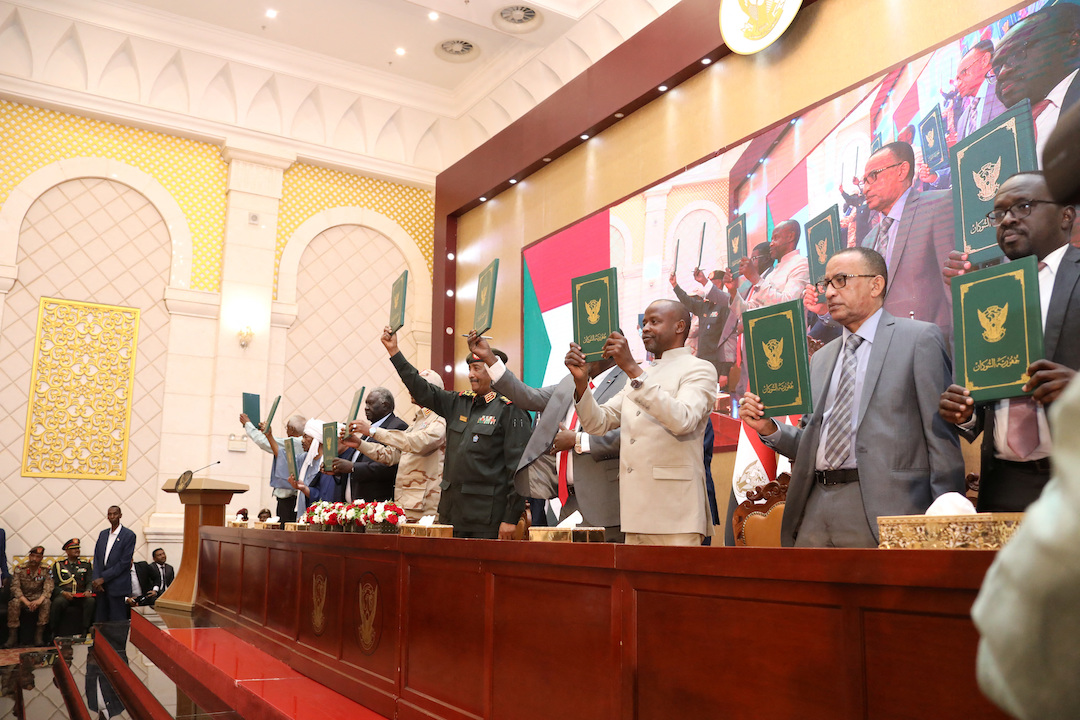 Signatory parties stand and raise signed copies of the agreement between military rulers and civilian powers in Khartoum, Sudan December 5, 2022.