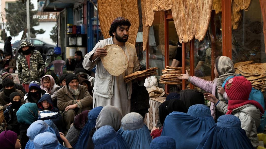 An Afghan man distributes bread to the people in need outside an eatery in Kabul on February 19, 2022. 