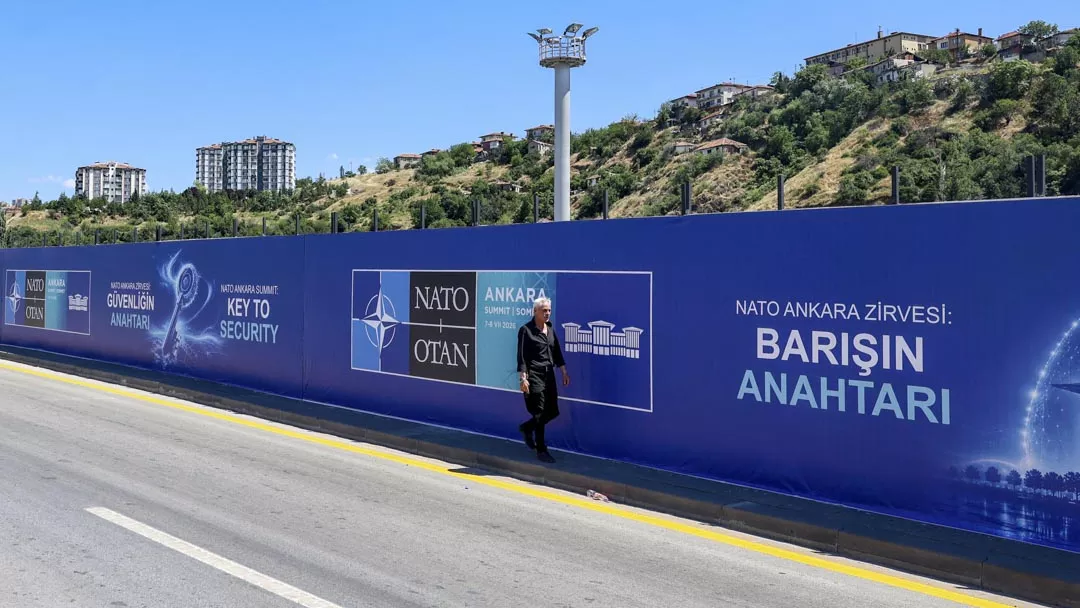 A local resident walks past billboards with the slogans “Key to Peace,” “Key to Security,” and “Shared Future in Peace”, displayed along the boulevard on the protocol route ahead of the NATO Summit in Ankara, on 26 June 2026. ADEM ALTAN / AFP