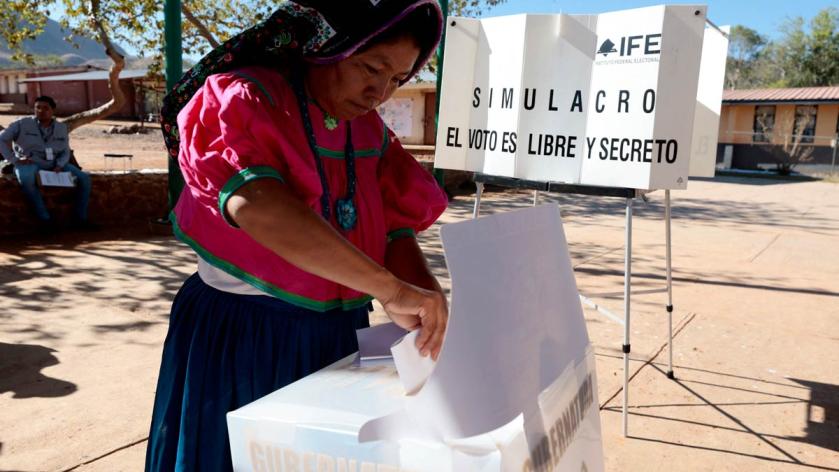 A Wixarika Indigenous woman casts her vote at an elementary school during a mock election day drill as part of the training given by officials of the National Electoral Institute (INE) ahead of the upcoming June 2 elections in Tuxpan de Bolaños, Jalisco State, Mexico, on May 18, 2024. Mexican Indigenous people are preparing to participate in the upcoming elections, considered fundamental for a country shaken by inequality, a deep recession, and drug-related violence. ULISES RUIZ / AE / AFP
