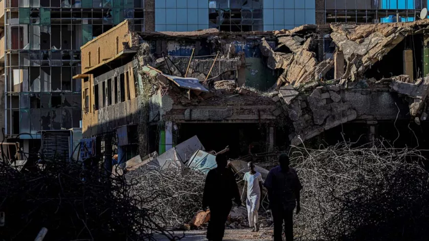 Sudanese men walk past destroyed building in the capital Khartoum on April 16, 2026. Of the nearly four million people -- around half Khartoum's pre-war population -- who fled during the conflict, more than 1.8 million have returned over the past year. 